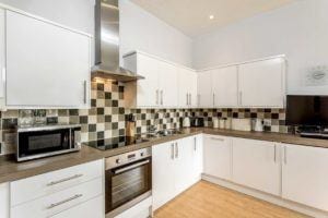 Bright white fully stocked kitchen with monochrome tiles