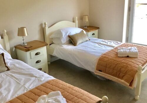 Matching twin beds with fresh white linen in Devon self catering home