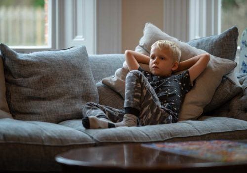Child relaxing wathcing TV on a sumptiuos couch