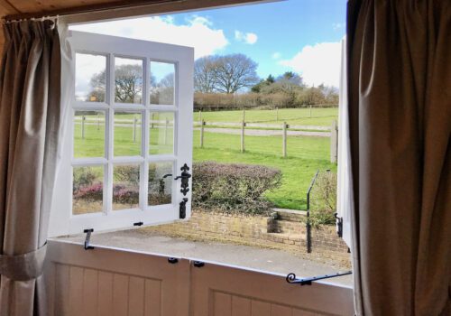 View through a stable patio door out to rolling fields