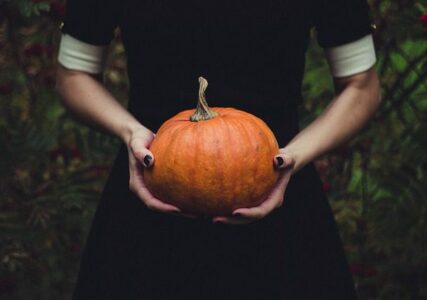 Gothic woman holding pumpkin in a forest